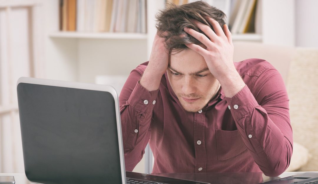 man holding head in frustration at computer